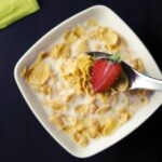 Immagine di una scatola di cereali con avvertenze sulla salute e ingredienti poco salutari.