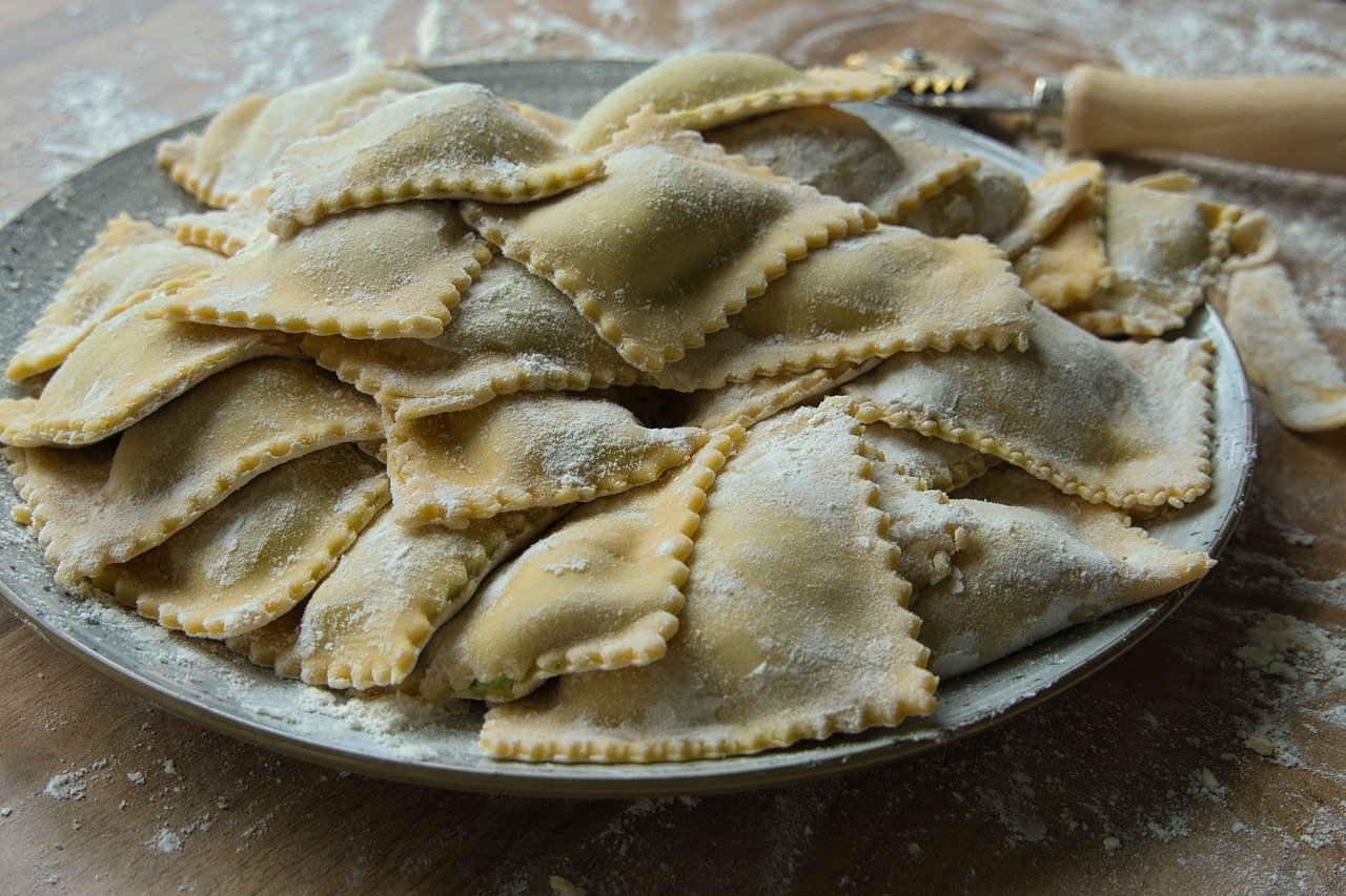 Ravioli freschi fatti in casa con ripieno cremoso su un tavolo di legno.